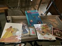 Photo showing multiple paper doll sheets and clothing on a cart.