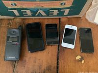 Overview of all five phones, three Apple iPhones and two Motorola phones placed on wooden surface.