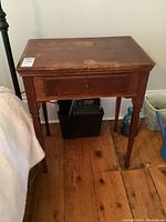 Front view of the vintage Singer sewing machine side table showing drawer and legs.