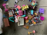 Overview of assorted doll house furniture and toys scattered on floor showing variety of colors and types