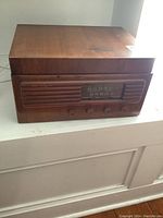 Front and top view of vintage wood cased record player and radio showing wood finish and overall box shape.