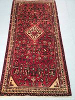 Full view of rug showing red field with geometric and floral motifs