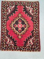 Full view of small Persian Hamedan rug showing central geometric medallion in red, brown and olive green with floral border.