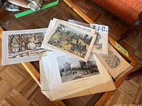 Top view of a stack of antique and vintage prints and book pages with visible aged paper and various historic scenes.