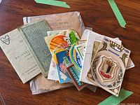 Overhead photo showing multiple antique pamphlets, vintage travel stickers, and a badge.