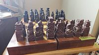 Chinese chess set showing all carved stone pieces arranged on wooden folded chessboard box. One bishop missing as noted by seller.