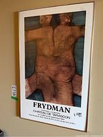 Full view of framed Frydman gallery poster showing artwork with brown and blue abstract nude figures and exhibition details below.