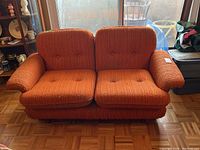 Front view of two seat orange sofa with lambs wool upholstery and button tufting.