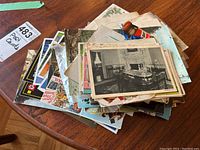 Pile of assorted vintage postcards, Christmas cards, advertising and ticket stubs laid on a wooden table.