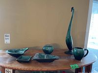 Front view of all six pottery pieces arranged on a wooden surface under natural light against beige wall.