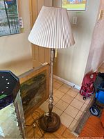 Full view of the turned wood floor lamp with pleated fabric shade, unlit, showing its size and design in room context