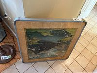 Top view of the card table showing scenic cardboard top with landscape image and visible stains and scratches.