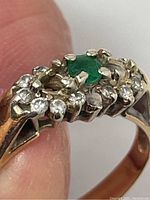 Close-up of ring showing green emerald centre and surrounding diamonds