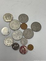 Overview of assorted collectable coins including US, Canada, Mexico, Hong Kong, Australia, Bermuda, Jamaica, Spain with various shapes including round and scalloped edges.