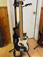 Full front view of bass guitar on stand showing body shape, finish, pickguard, pickups and hardware
