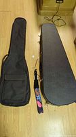 Both guitar carrying cases displayed side by side, showing difference between hard case and soft bag with additional accessories.