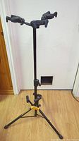 Full view of the Hercules triple guitar stand showing tripod base and three adjustable arms with yokes