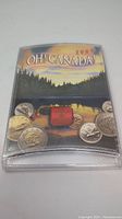 Front view of sealed Oh Canada 2000 uncirculated coin set case showing Canadian landscape artwork and coins