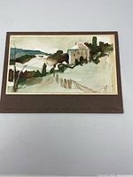 Original watercolour painting showing a rural house near a landscape of hills and a fence in front, mounted on brown matting.
