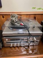 Front view of the Sony turntable on top of the Sony receiver with visible RCA cables coiled on top.