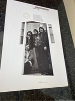 Close-up showing one litho poster with The Beatles posing in a doorway, black and white.