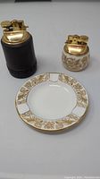 Photo showing the set of two lighters and ashtray with gold floral decoration.