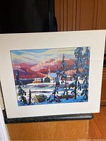 Print of a vivid winter landscape featuring a cabin, snow-covered trees, and mountains under a colorful sky, with white mat border.