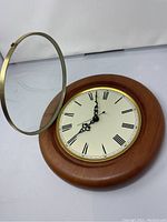 Close-up showing open glass cover with bronze frame and clock face with Roman numerals and black ornate hands.