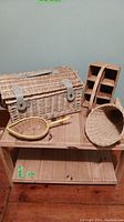 Wicker picnic basket closed, showing additional assorted baskets on shelf underneath