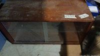 Top and front view of wooden display case showing surface wear and sliding glass doors.