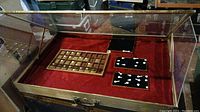 Top view of the portable display case showing the glass lid, red velvet interior, wooden grid tray, and black boards with jewelry positions.