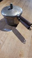 Vintage Presto Pressure Cooker with wooden handle sitting on wooden surface.