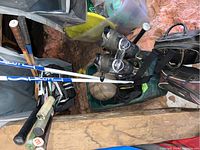 Photo showing multiple sports items including two bowling balls in bags, tennis rackets, Little League baseball bat and ski poles, stored together in attic space