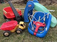 Wide view of all items in lot on grass showing the Little Tikes slide, blue swing, yellow dump truck, and red Fisher-Price wagon.