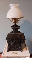 Full view of the vintage cast iron stove lamp with milk glass hobnail shade on top, showing detailed stove design and white shade.