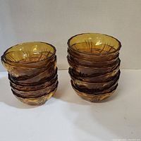 Two stacks of amber glass bowls, one with seven bowls and one with six bowls, showing textured amber glass with rippled edges and fine lines.