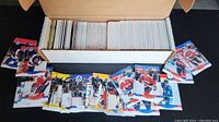 Box of hockey cards, showing the storage box filled with cards and several cards spread out in front.