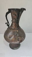 Full view of the bronze pitcher showing its shape and handle