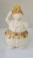 Front view of ceramic cookie jar showing man figure with raised hand and tall brown-glazed hat.