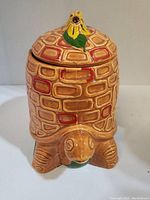 Front view of turtle-shaped cookie jar showing textured bricked pattern and detailed turtle head and feet.