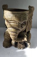 Front view of an elephant-shaped ceramic jar showing detailed facial features and hollow interior opening at the top.