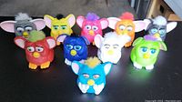 Photo of 10 collectible McDonald's Furby toys in various colors and styles arranged on a dark surface.
