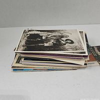 A stack of vintage postcards with a black and white image of a person in western clothing on top.