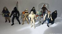 Photo showing full set of 9 Star Wars action figures arranged in two rows on white surface