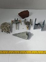 Photo showing six Star Wars die cast vehicles on white backdrop with measuring tape for scale, approximate size 2-4 inches each.