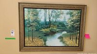 Front view of the framed textured nature landscape painting showing trees, river, and arched bridge.