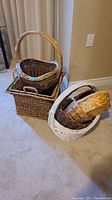 Front view of stacked dark brown square basket, smaller rectangular basket inside, and white oval basket with handle placed beside them.