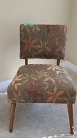 Front view of hostess chair showing patterned upholstery and wooden legs.