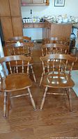 Set of six vintage wooden chairs arranged in two rows on wooden floor, showing chair design and finish