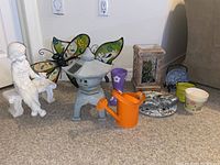 Primary photo showing entire lot with all garden accessories including statue, solar light, watering can, boots pot, butterfly decorations